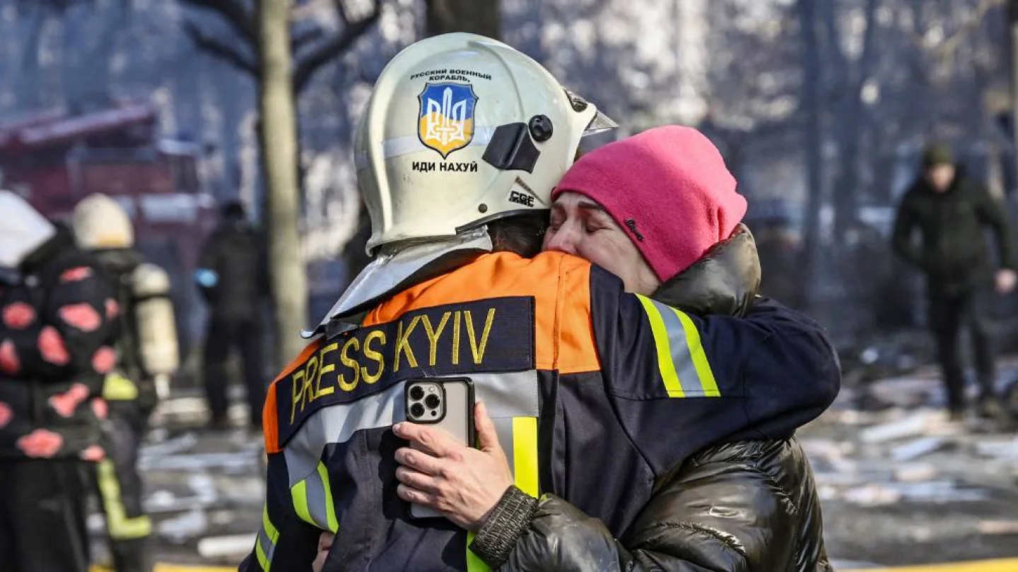 15 Mart tarihli bu fotoğrafta; bir itfaiyecinin Kiev'deki Rus saldırısında hasar alan apartmanın önünde bir kadını kucaklayarak teselli ettiği görülüyor. Foto: AFP