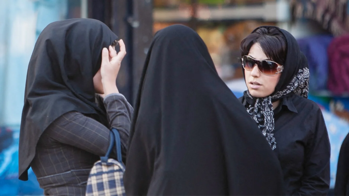 Tahran'da iki başörtülü “ahlak polisi” kadınlarla konuşurken bir İranlı kadın başörtüsünü düzeltiyor/foto: AFP