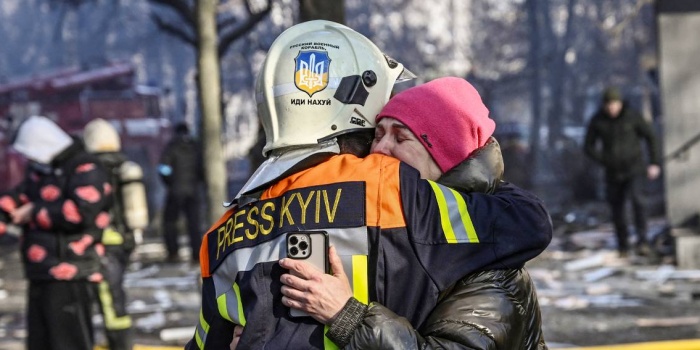 15 Mart tarihli bu fotoğrafta; bir itfaiyecinin Kiev'deki Rus saldırısında hasar alan apartmanın önünde bir kadını kucaklayarak teselli ettiği görülüyor. Foto: AFP