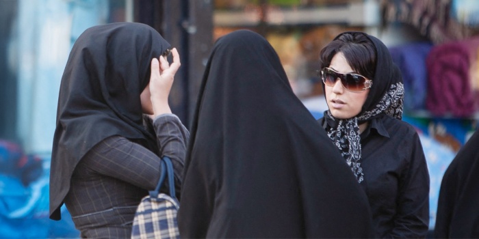 Tahran'da iki başörtülü “ahlak polisi” kadınlarla konuşurken bir İranlı kadın başörtüsünü düzeltiyor/foto: AFP